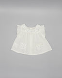 Blusa bebé niña blanca plumeti con cuello volante, mangas mariposa y bolsillos con estampado floral azul