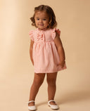 Vestido bebé niña vichy rosa con volantes, lazos delanteros y mangas mariposa, combinado con zapatos blancos.
