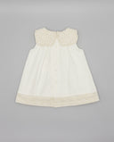 Vestido bebé blanco sin mangas con cuello marinero bordado en beige, botones centrales y bajo con encaje floral.