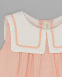Vestido de bebé de lino rosa sin mangas con cuello marinero blanco y ribete ondulado en color salmón