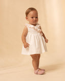 Vestido bebé niña blanco piqué sin mangas con volante cruzado y detalles en rosa, zapatos merceditas rosas