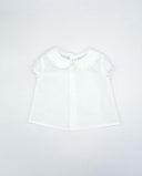 Blusa bebé blanca plumeti con cuello bebé de puntilla y manga farol corta para niña