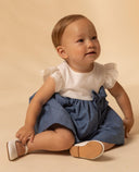 Vestido bebé niña blanco y azul con cuerpo liso, mangas volante con encaje y falda fruncida con lazo lateral