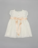 Vestido de bebé blanco roto en gazar con encaje, botones nacarados y lazo de raso salmón en la cintura