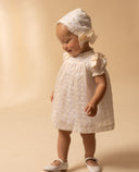 Vestido bebé niña blanco roto sedeta bordada con volante, lazos y capota a juego, zapatos blancos