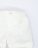 Bermuda de lino color crudo con cintura elástica, bolsillo trasero con botón y textura cuadriculada tonal