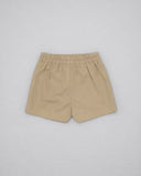 Bermuda infantil color beige arena de sarga con cintura elástica fruncida y bajo recto sobre fondo gris