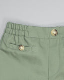 Bermuda de loneta verde sage con cintura elástica y botones dorados, detalle de bolsillo lateral cosido