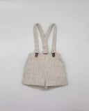 Bermuda infantil de lino rústico beige con tirantes y pinzas metálicas doradas para niño