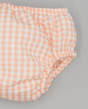 Cubrepañal bebé de tela vichy a cuadros medianos en color salmón y blanco con cintura y perneras elásticas.