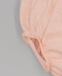 Cubrepañal de lino liso en color rosa palo con elástico fruncido en pernera, detalle de tejido artesanal suave para bebé.