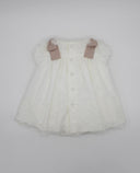 Vestido de bebé blanco en tul bordado con lazos rosa palo en hombros, botones frontales y bajo festoneado