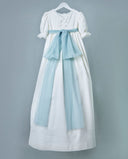 Vestido de comunión blanco en piqué con mangas abullonadas, encaje y lazo azul celeste en tul largo.