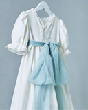 Vestido de comunión blanco piqué con mangas abullonadas, encaje, botones perla y fajín de tul azul celeste en percha
