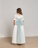 Vestido de comunión blanco en piqué con lazo de tul azul en la espalda y mangas cortas con volante de encaje