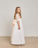 Vestido de comunión niña en gazar blanco con cuerpo beige, mangas encaje y lazo rosa palo en espalda.
