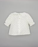 Blusa bebé blanca con estampado floral azul, cuello con volante, manga farol y botones nacarados en espalda