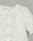 Blusa infantil blanca con estampado floral azul, cuello Peter Pan con volantes, lazos a rayas y manga farol