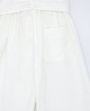Detalle trasero de pantalón blanco roto de popelín con cinturón anudado, cintura elástica y bolsillo posterior parche.