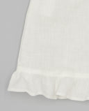 Detalle de bajo con volante fruncido en blusa de lino blanco roto con acabado suave y textura natural