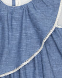 Vestido infantil de lino flameado azul sin mangas con volante diagonal y ribete de encaje blanco