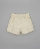 Shorts infantil color crema con bordado floral tipo broderie, cintura elástica y bajo con acabado guipur ondulado.
