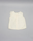 Blusa infantil sin mangas color crudo de lyocell con volante delantero y botones blancos centrales