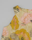 Blusa sin mangas con estampado floral grande en tonos amarillo, rosa y verde, con hombros caídos y cuello redondo.