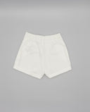 Short blanco de sarga con cintura elástica, bolsillos y dobladillo vuelto, fondo gris neutro.