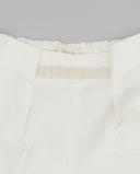 Detalle interior de short blanco en sarga con cintura elástica fruncida y cinta decorativa beige tejida.