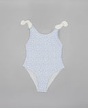 Bañador entero azul celeste con estampado floral blanco y tirantes con nudo, ideal para playa y piscina.